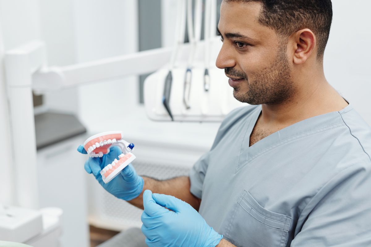 A dentist in a clinic holding a model of teeth